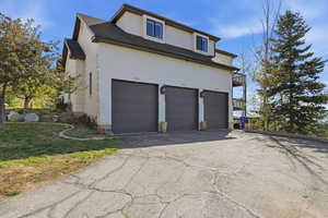 View of property exterior with asphalt driveway, stucco siding, and an attached garage