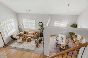 Living room with suspended lighting, wood finished floors, and vaulted ceiling