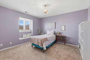 Bedroom featuring light colored carpet and hanging lights