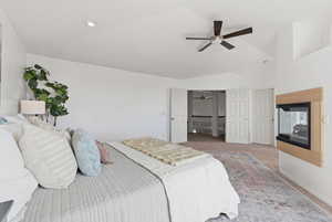 Bedroom with vaulted ceiling, light colored carpet, and ceiling fan