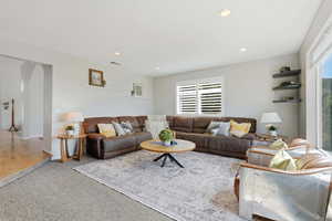 Living area with carpet flooring, arched walkways, and recessed lighting