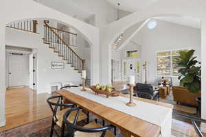 Dining area with light wood-style flooring, arched walkways, and vaulted ceiling