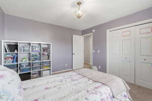 Carpeted bedroom with a closet and hanging lights