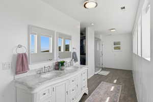 Full bath featuring double vanity, dark wood-style flooring, and a stall shower