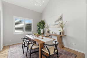 Dining space with lofted ceiling, light wood finished floors, and suspended lighting