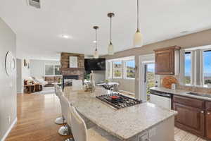 Kitchen with light stone counters, a breakfast bar area, a kitchen island, pendant lighting, and two tone color scheme