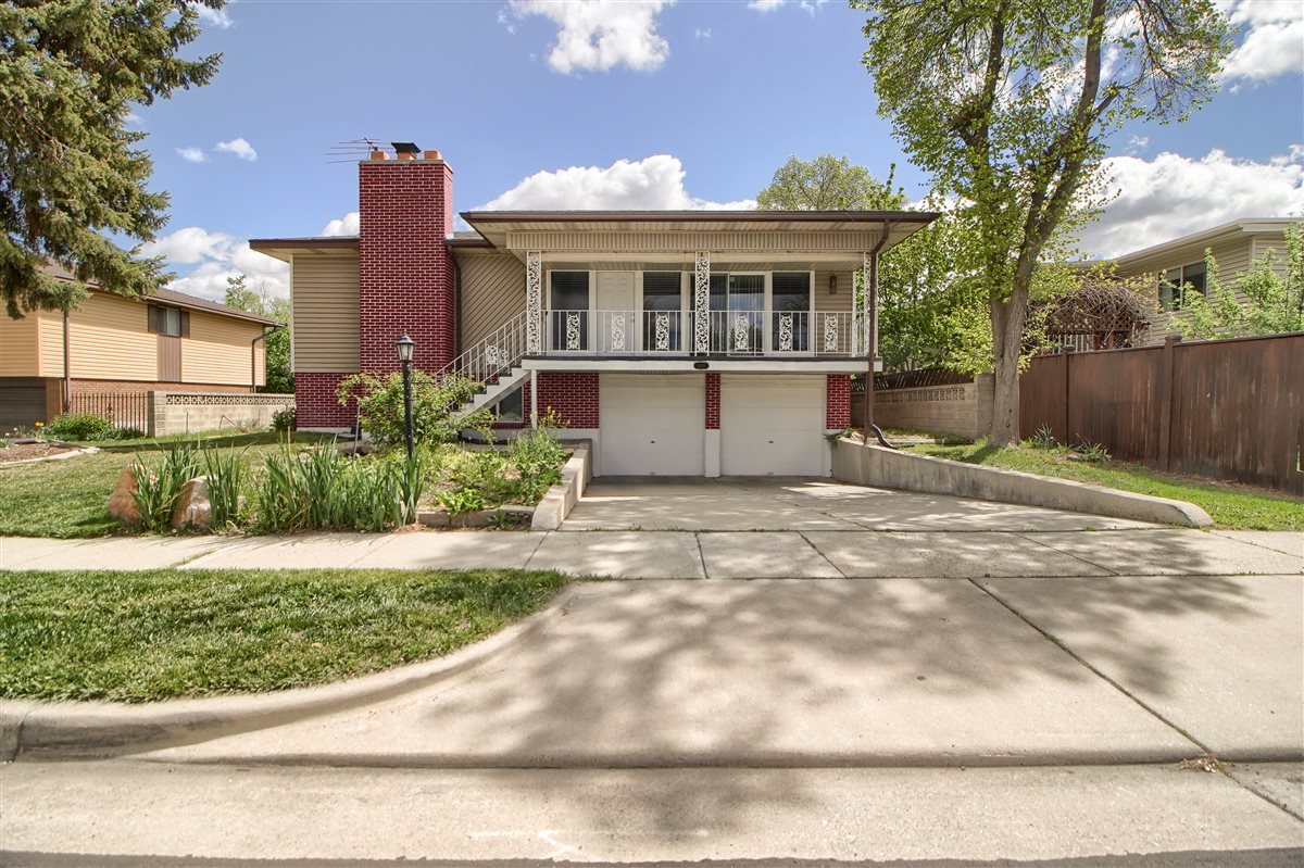 View of front of property with a garage, covered porch, brick siding, driveway, and a chimney