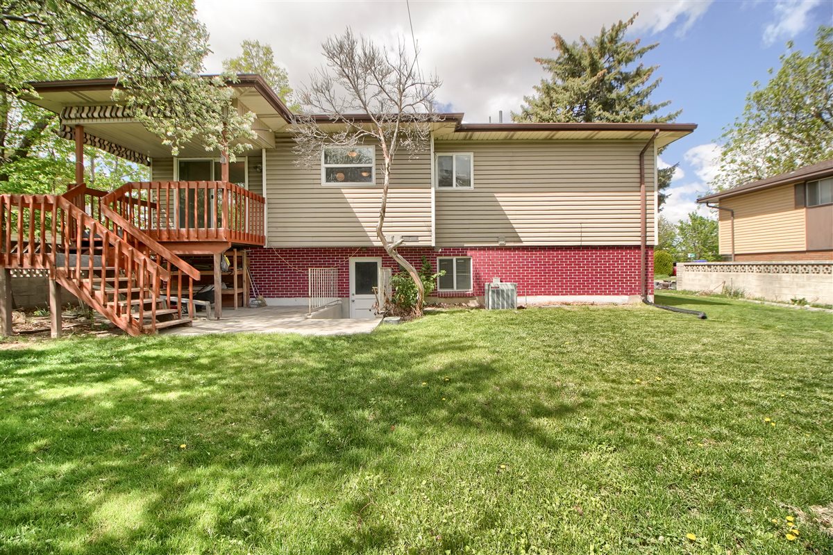 Back of property featuring a patio area, brick siding, a lawn, and a wooden deck