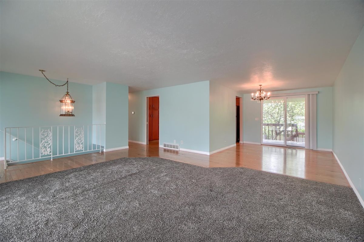 Empty room featuring hanging lights and light colored carpet