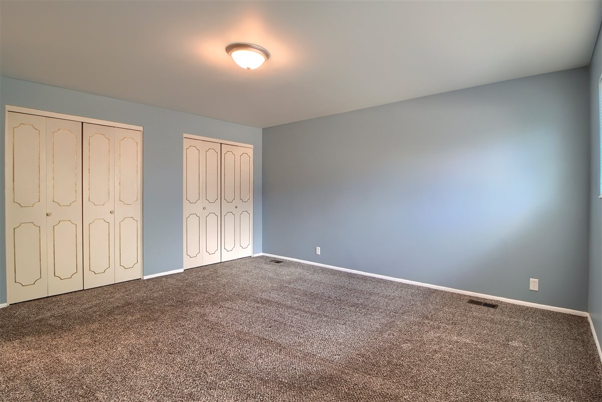 Unfurnished bedroom with carpet floors and multiple closets