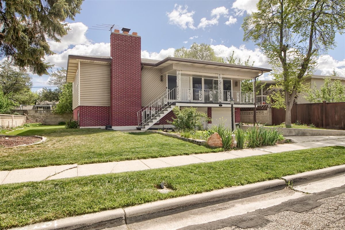 View of front of house featuring brick siding, a chimney, an attached garage, and covered porch