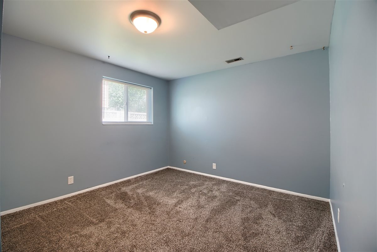 Spare room featuring dark colored carpet and baseboards