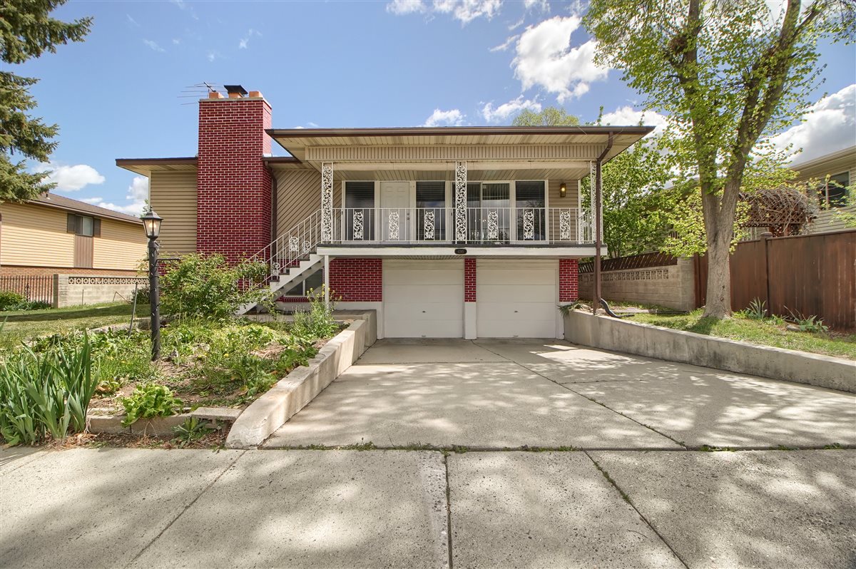 View of front of property with a porch, a garage, a chimney, driveway, and brick siding