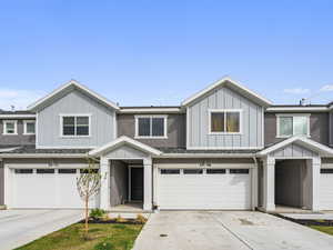 View of front of property featuring board and batten siding, an attached garage, and driveway