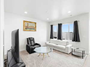Carpeted living area with recessed lighting and baseboards