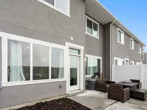 Rear view of property featuring a patio, stucco siding, and an outdoor living space with a fire pit