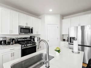 Kitchen featuring stainless steel appliances, white cabinetry, recessed lighting, and light stone counters