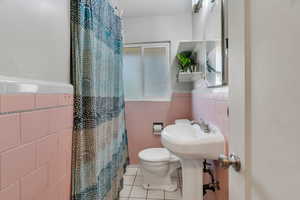 Full bath featuring a stall shower, tile walls, tile patterned flooring, and a wainscoted wall
