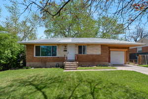 View of front of home with a front lawn, concrete driveway, brick siding, and an attached garage