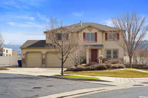 Traditional-style home with driveway, stucco siding, roof with shingles, and a garage