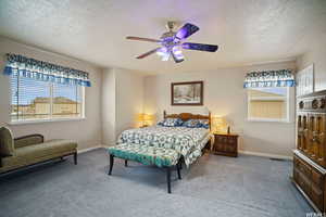 Bedroom featuring a textured ceiling, carpet floors, multiple windows, and ceiling fan