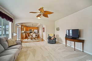 Living area with ceiling fan, arched walkways, light colored carpet, and recessed lighting