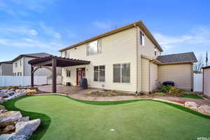 Rear view of house with a patio, a fenced backyard, a pergola, and an area to practice putting