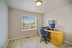 Office space featuring light wood-style flooring and a textured ceiling
