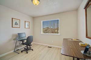 Office space featuring light wood-style floors and a textured ceiling