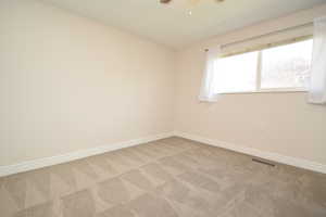 Unfurnished room featuring light colored carpet and a ceiling fan