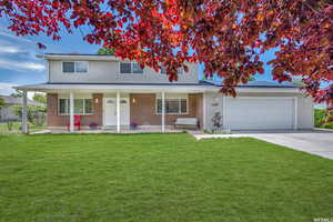 Traditional home featuring concrete driveway, a garage, brick siding, and a front yard