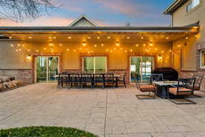 View of patio with outdoor dining space, a fire pit, and grilling area