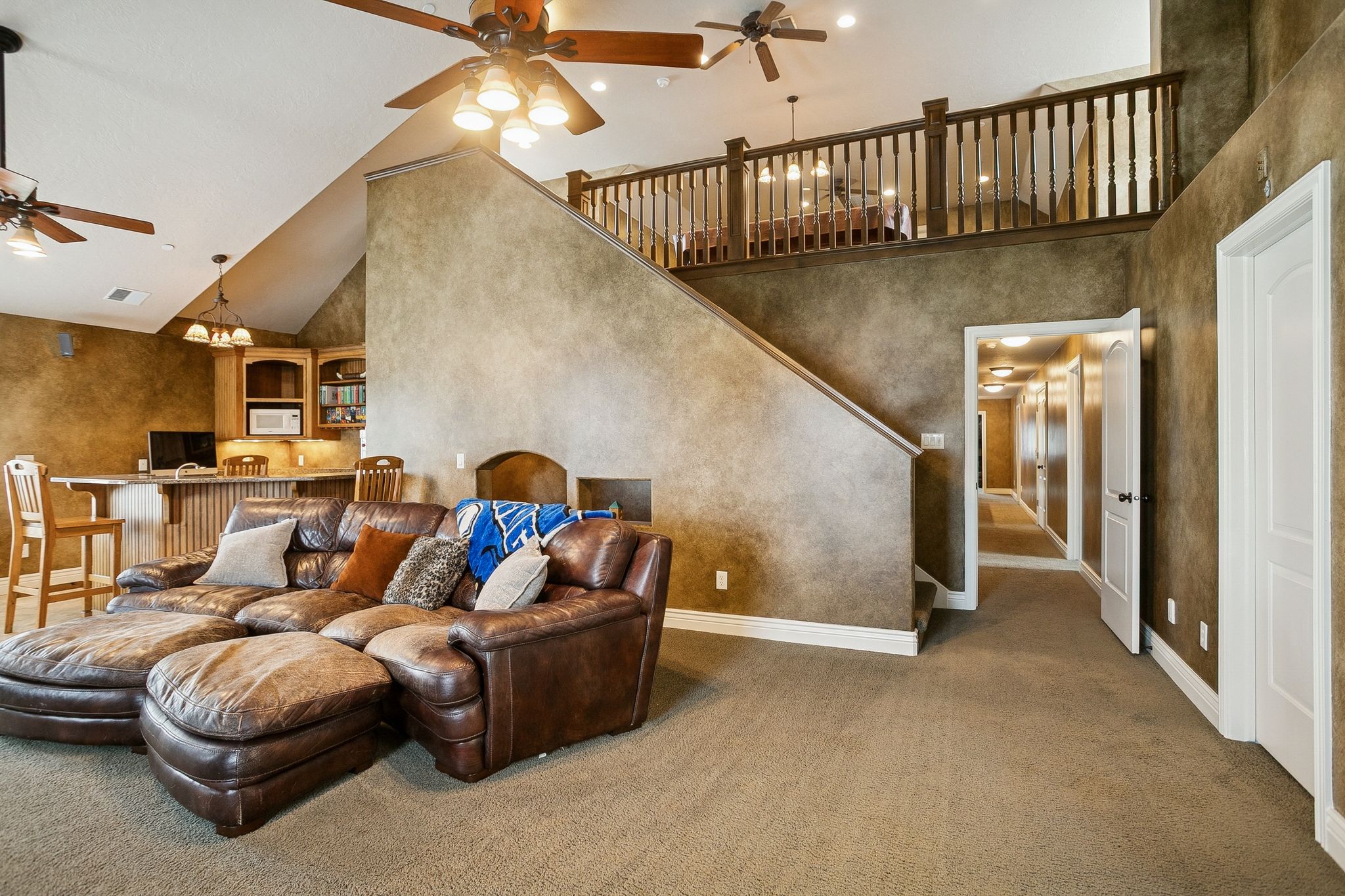 Living room with high vaulted ceiling, ceiling fan, carpet, and stairs