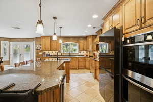 Kitchen featuring a kitchen bar, french doors, freestanding refrigerator, brown cabinets, and recessed lighting