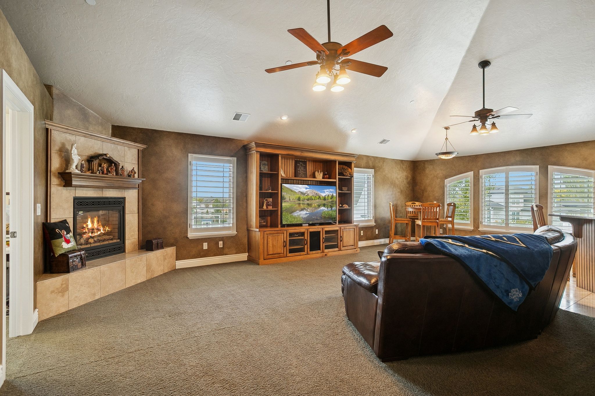 Living area with a tile fireplace, lofted ceiling, carpet, a textured ceiling, and ceiling fan
