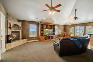 Living area with a tile fireplace, lofted ceiling, carpet, a textured ceiling, and ceiling fan