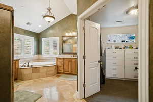 Bathroom featuring vaulted ceiling, a bath, vanity, and light tile patterned floors