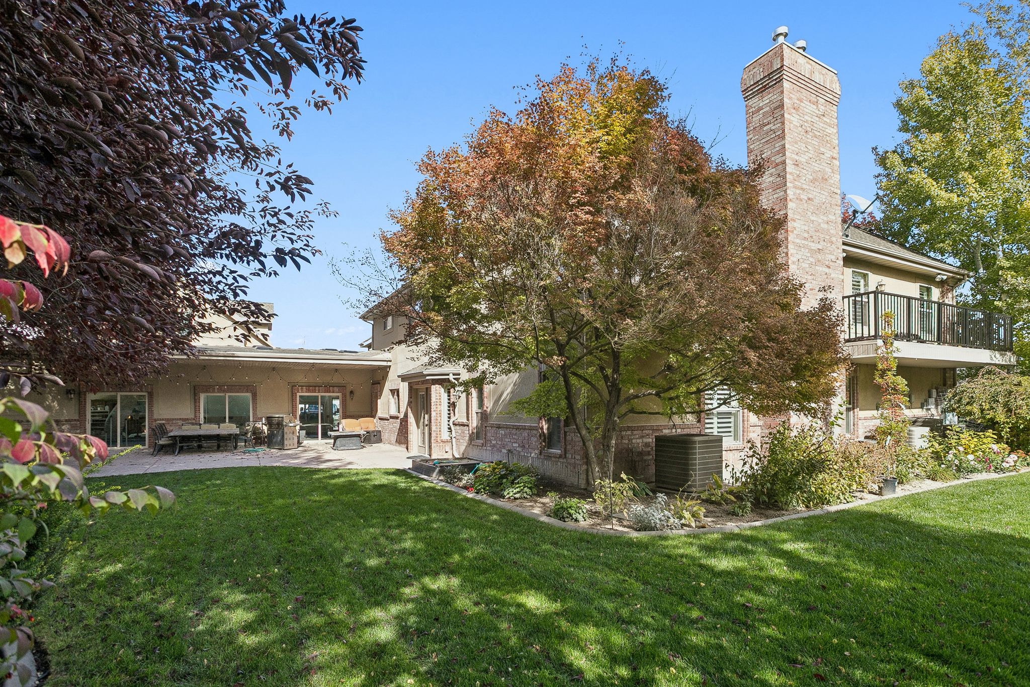 Rear view of house featuring a lawn, a chimney, stucco siding, and a patio area