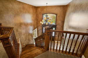 Staircase featuring a chandelier, a high ceiling, and hardwood / wood-style floors