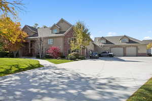 Traditional home featuring driveway, a front lawn, brick siding, and an attached garage
