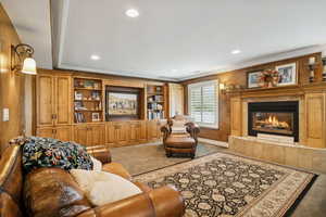 Carpeted living area with a tiled fireplace, recessed lighting, ornamental molding, and built in features