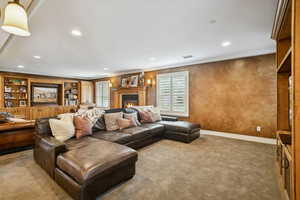 Carpeted living room with plenty of natural light, a lit fireplace, ornamental molding, and recessed lighting