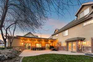 Back of house at dusk with a patio, stucco siding, and a yard