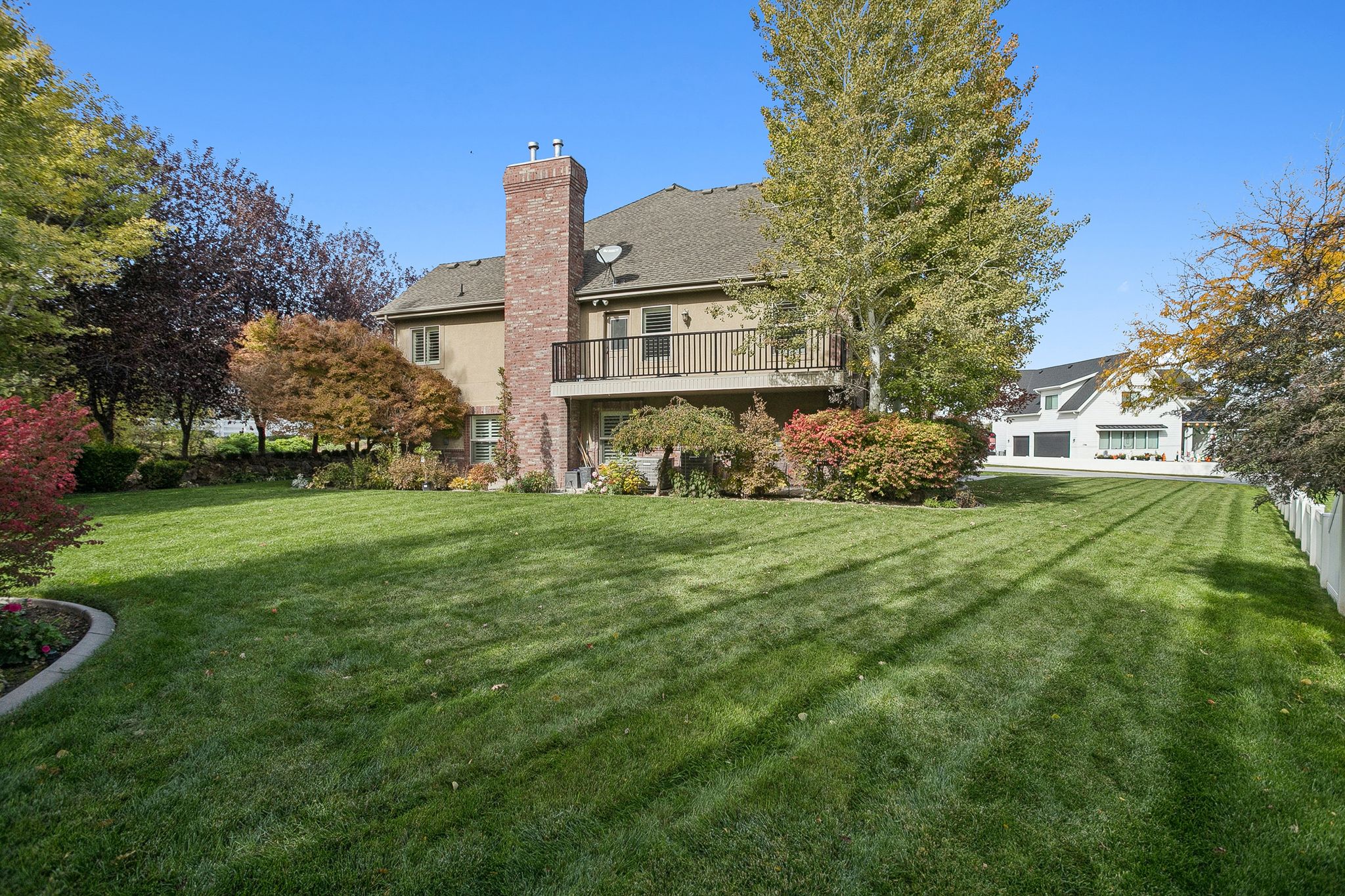 Rear view of house with a yard, a chimney, stucco siding, and a shingled roof