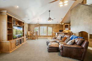 Living area with high vaulted ceiling, ceiling fan, light colored carpet, and arched walkways