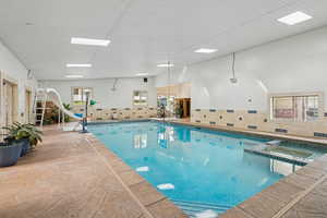View of swimming pool with a pool with connected hot tub and a skylight