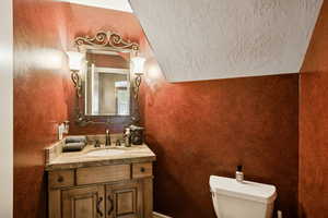 Half bath featuring vanity and a textured wall