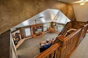 Carpeted living room with a high end fireplace, lofted ceiling, a ceiling fan, and a textured ceiling