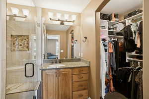 Bathroom with vanity, a shower stall, a walk in closet, and connected bathroom