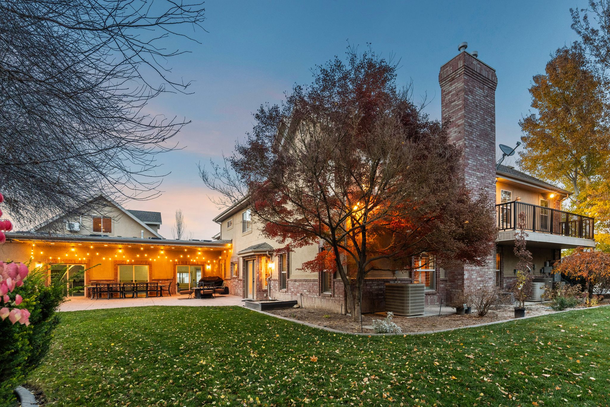 Back of house featuring a lawn, a chimney, a patio, and brick siding